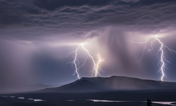 Kilatan petir yang dramatis menerangi pegunungan dan danau saat badai petir dahsyat melanda, awan gelap di langit menunjukkan kekuatan alam.